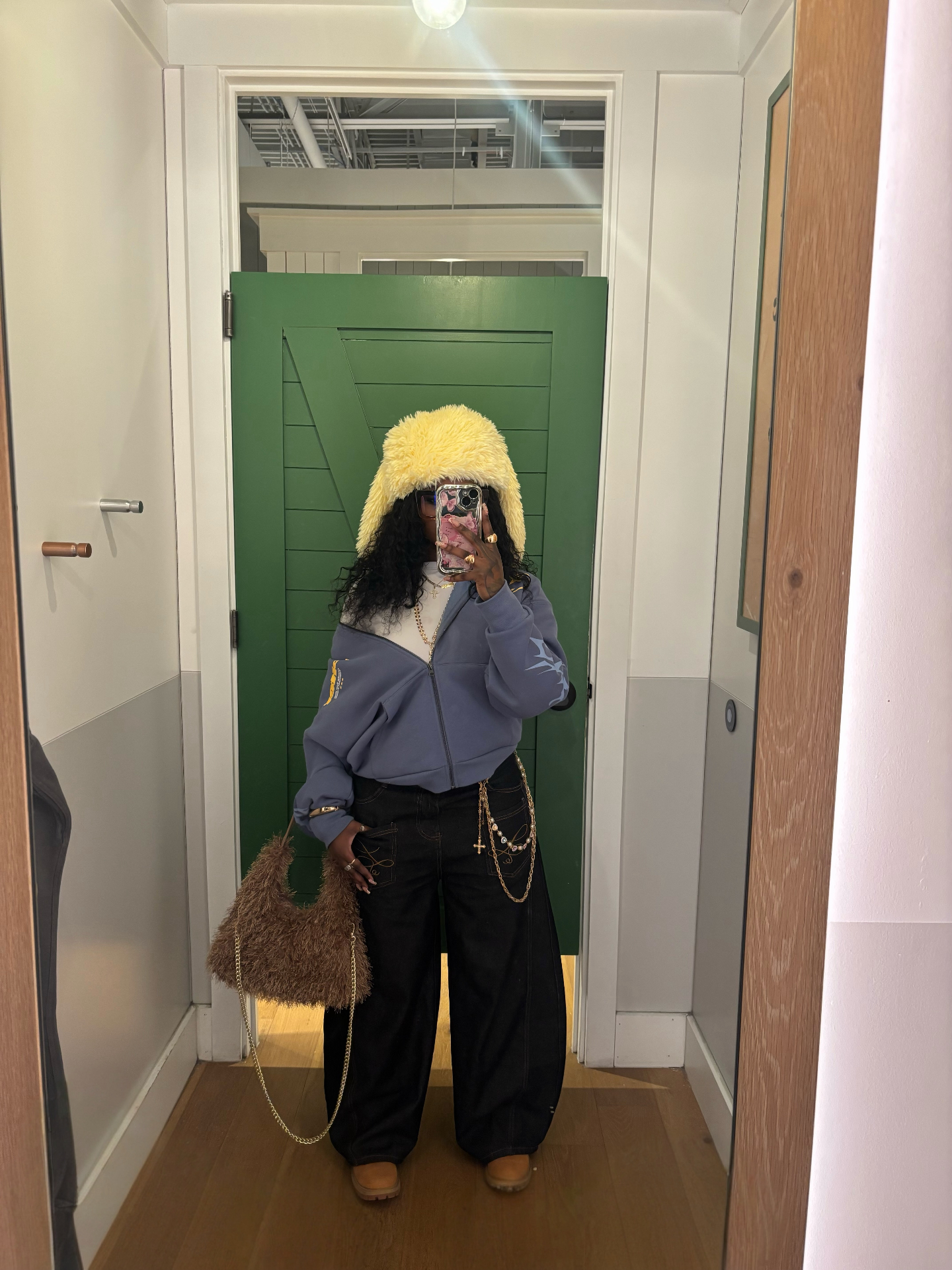 Cool-toned styled look with oversized fur hat, chain details, and wide-leg trousers